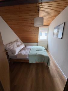 a bed in a room with a wooden ceiling at Ferienwohnung Bergblick Bad Staffelstein in Bad Staffelstein