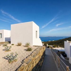 a white house with a stone wall and a walkway at Halo Tinos - ARTEMIS in Tinos
