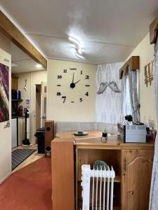 a large clock on a wall in a living room at Willows Retreat in Reighton