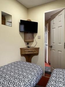 a bedroom with a bed and a dresser with a television at Willows Retreat in Reighton