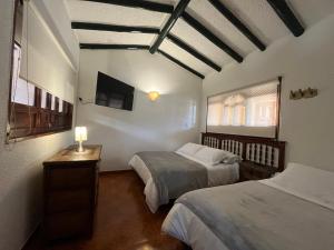 a bedroom with two beds and a tv on the wall at Posada Santa Lucía de Cucaita in Cucaita