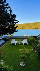 two white benches sitting in the grass near the water at Çeşme Seaside House in Çeşme