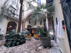 a courtyard with palm trees and tables and chairs at Quintocanto Hotel & Spa in Palermo