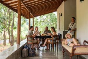 a group of people sitting around a table on a porch at WildEscape, Yala Blocks 3, 4 & 5 in Buttala