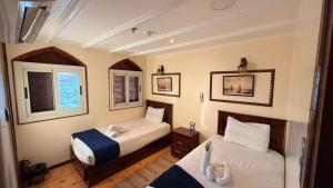 a small bedroom with two beds and a window at Dahabiya Queen Tyi II in Luxor
