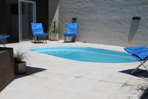2 Stühle und ein Pool mit zwei blauen Stühlen in der Unterkunft Talu Apart Hotel in San Rafael