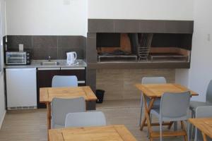una cocina con mesas y sillas de madera en una habitación en Talu Apart Hotel en San Rafael