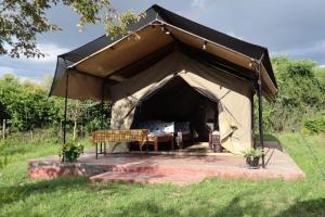 a tent with a bed in it in a field at Ntito Mara lodge in Maasai Mara National Reserve