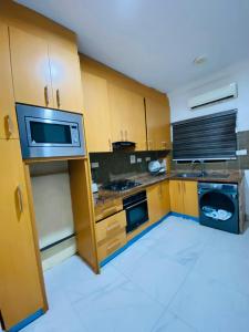 a small kitchen with wooden cabinets and a microwave at Unique luxury duplex in Lekki