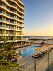 a large building with a swimming pool next to a beach at FIRST RESIDENCe in Mamaia