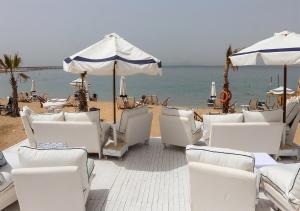 a group of white chairs and umbrellas on a beach at Paradise Inn Beach Resort in Alexandria