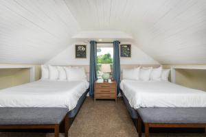 two beds in a room with two windows at The Legacy Inn in Luray