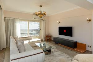 a living room with a white couch and a tv at 3BR Beach Front Chalet On RedSea in Ain Sokhna