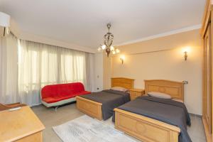 a bedroom with two beds and a red chair at 3BR Beach Front Chalet On RedSea in Ain Sokhna