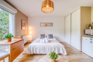 a bedroom with a white bed and a large window at Jardins de Flore in Mérignac