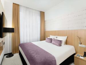 a bedroom with a large bed with purple pillows at Nemzeti Hotel Budapest - MGallery Collection in Budapest