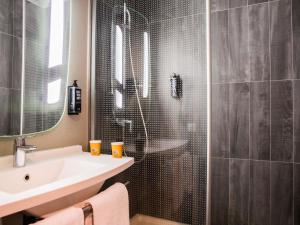 a bathroom with a shower with a sink and a mirror at ibis Paris Bercy Village in Paris