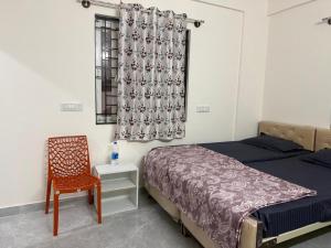 a bedroom with a bed and a chair and a window at VR Colive in Kammasandra