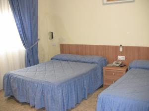 a hotel room with two beds and a telephone at Hotel Los Hermanos in Ocaña