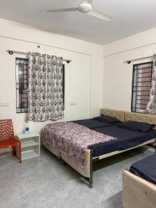a bedroom with a bed and a chair and windows at VR Colive in Kammasandra