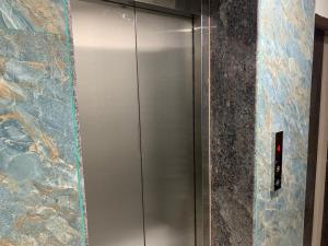 a metal elevator in a bathroom with a stone wall at VR Colive in Kammasandra