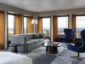 a living room with a couch and chairs and windows at Sofitel Melbourne On Collins in Melbourne +182 photos