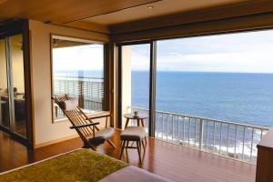 a bedroom with a balcony with a view of the ocean at Inatori Tokai Hotel Yuen in Higashiizu