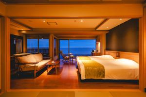 a bedroom with a bed and a view of the ocean at Inatori Tokai Hotel Yuen in Higashiizu