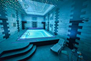 a blue room with a swimming pool and a chair at Hotel Jasmin All Inclusive in Truskavets