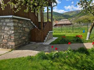 a garden with a stone fence and red flowers at La Umbra Muntilor Traditional House in Ocoliş