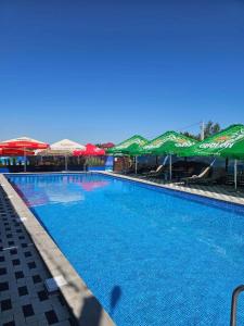 a large swimming pool with umbrellas and tables and chairs at Эко Парк in Bălţi +52 photos