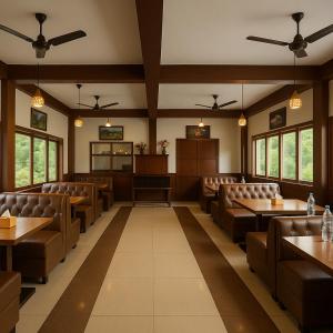 a restaurant with brown leather chairs and tables and windows at Chaman Vatika in Kasol