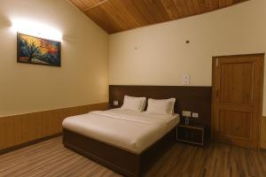 a bedroom with a bed and a painting on the wall at Chaman Vatika in Kasol