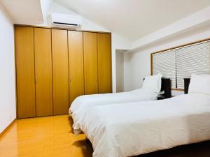 two beds in a room with wooden cabinets at KiyomizuGaku Guesthouse in Keage