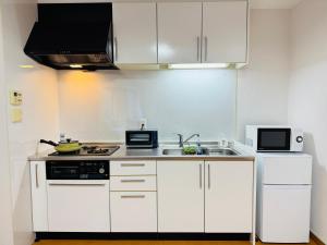 a small kitchen with white cabinets and a sink at KiyomizuGaku Guesthouse in Keage