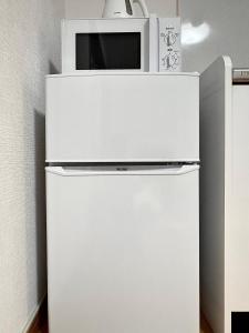 a white refrigerator with a microwave on top of it at KiyomizuGaku Guesthouse in Keage