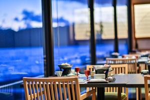 a dining room with tables and chairs and a large window at Inatori Tokai Hotel Yuen in Higashiizu
