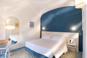 a bedroom with a white bed and a blue wall at Hotel Oasi Castiglione in Casamicciola Terme