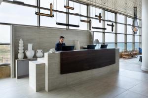 a man sitting at a counter with a laptop at Leonardo Plaza Haifa in Haifa +103 photos