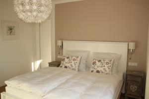 Un dormitorio con una cama blanca con almohadas y una lámpara de araña. en Ferienwohnung Ammersee by paul apartments, en Herrsching am Ammersee