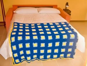 a bed with a blue and yellow blanket on it at Il Pergolato in Cannero Riviera