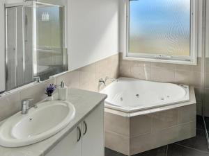 a bathroom with a tub and a sink and a window at Spotted Gum -Merrijig in Merrijig +5 photos