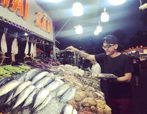 a man holding a plate of fish in a market at KHÁCH SẠN THU NGUYỄN - ngay BẾN NINH KIỀU, CHỢ ĐÊM in Can Tho