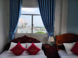 a bedroom with two beds and a window with blue curtains at KHÁCH SẠN THU NGUYỄN - ngay BẾN NINH KIỀU, CHỢ ĐÊM in Can Tho +47 photos