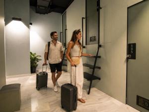 a man and a woman with luggage in an elevator at Hostel Superlativo Trinidad in Málaga