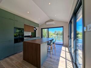 a kitchen with green cabinets and a bar with stools at Maison du Bord du Rhône in Saint-Pierre-de-Boeuf