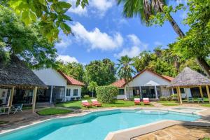 a pool in front of a house with trees at Driftwood Beach Malindi Palace in Malindi