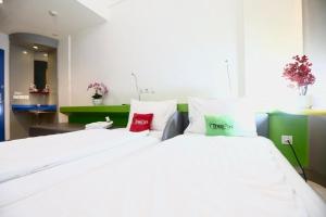 a bedroom with two beds with white sheets and red pillows at TreePark Hotel Jakarta Airport in Tangerang +3 photos