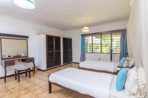 a bedroom with two beds and a desk and a mirror at Driftwood Beach Malindi Palace in Malindi