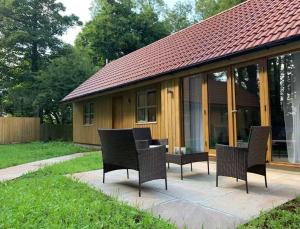 a patio with chairs and a table in front of a house at Maple Lodge Cottage in Blagdon